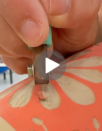Close-up of a DiamondCore® carving tool etching flower petal designs into bright orange underglaze on a clay surface.