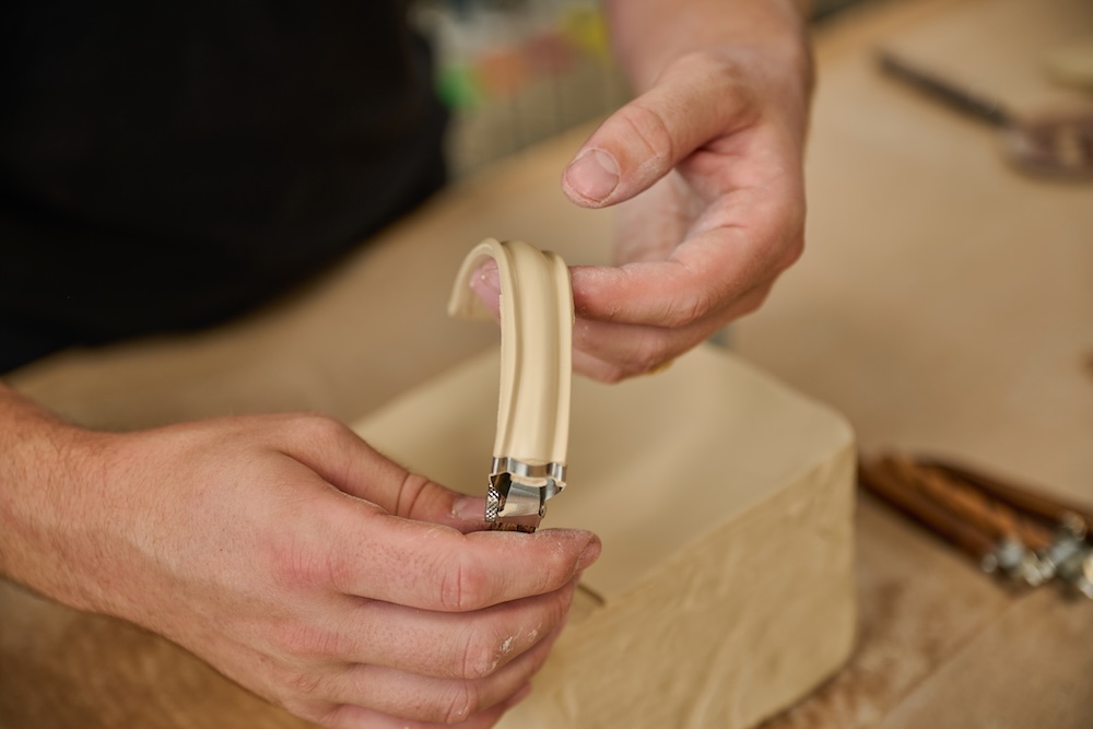 A person using the R207 extruder on clay to make a handle.
