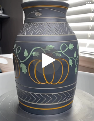 A tall vase featuring bold, intricate pumpkin and vine sgraffito carvings with green and orange underglaze.